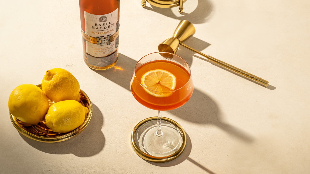 Basil Hayden® Subtle Smoke boutbon bottle and a cocktail and some lemons on a plate