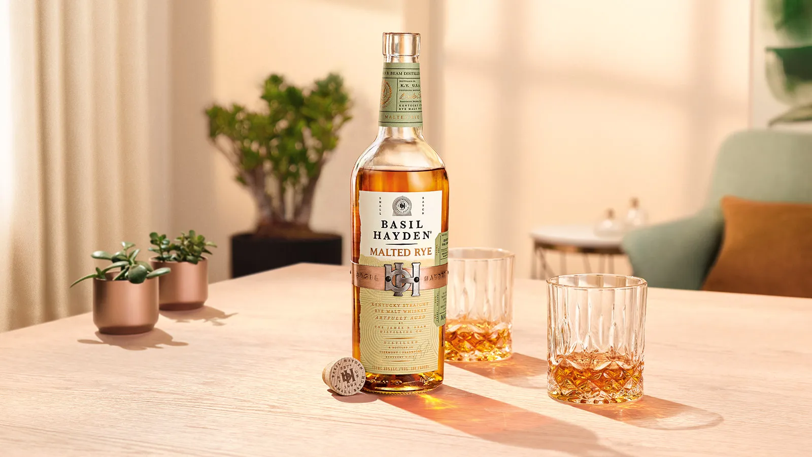 Basil Hayden® Malted Rye bottle on a table with cocktails