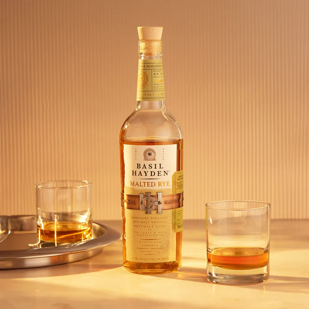 Basil Hayden® Malted Rye bottle on a table with cocktails