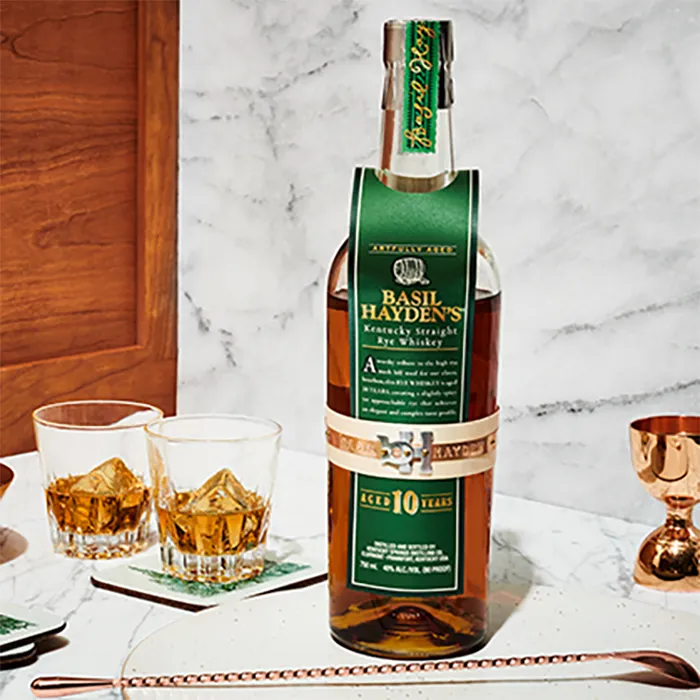 A bottle of Basil Hayden 10 Year Old Rye Whiskey and two glasses filled with the bourbon