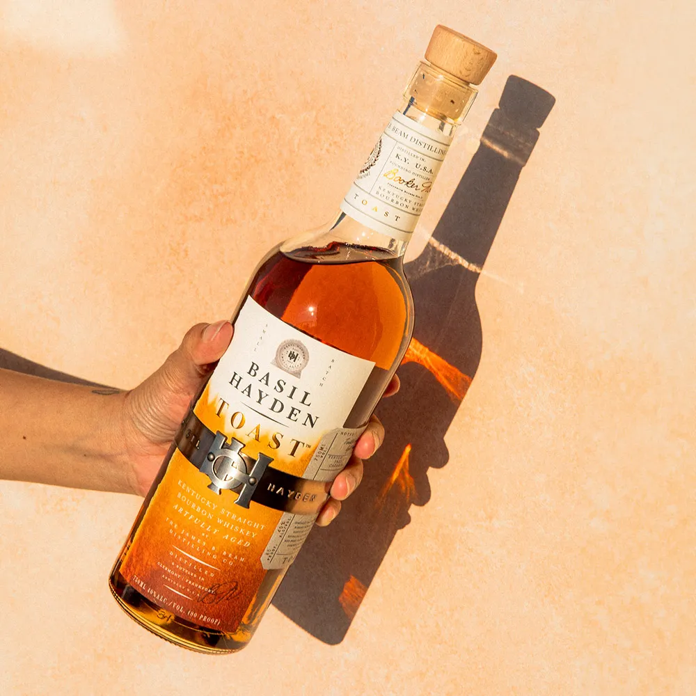 Hand holding a bottle of Basil Hayden Toast™